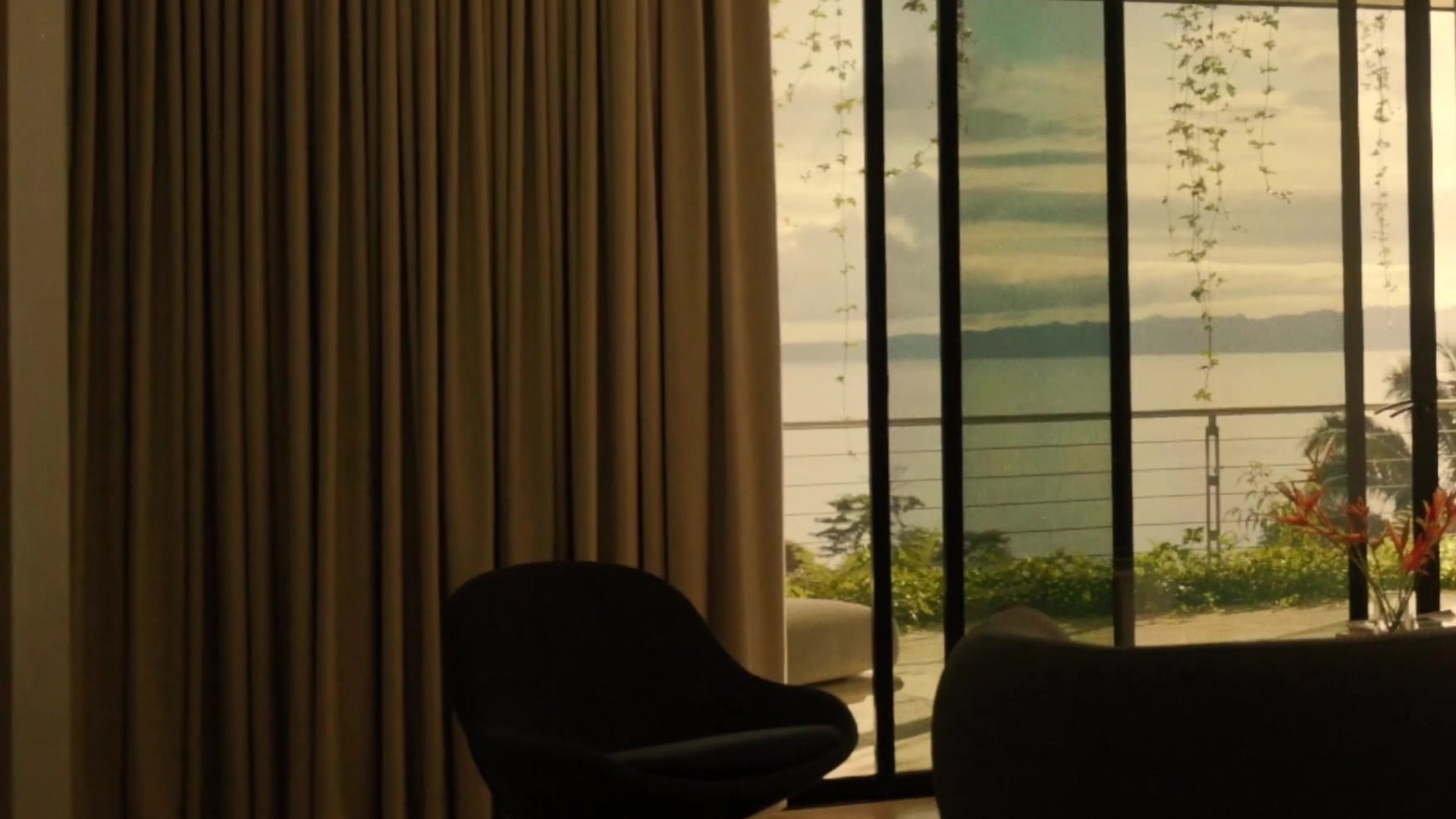 An armchair beside floor-to-ceiling windows overlooking the coast.